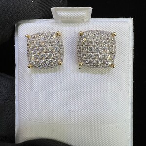 May include: A pair of gold square-shaped earrings with a pave setting of small round clear diamonds.