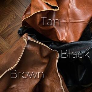 May include: Close-up of three leather items in tan, brown, and black. The tan item is at the top, the brown item is at the bottom left, and the black item is in the background. The word "Tan" is written on the tan item, "Black" on the black item, and "Brown" on the brown item.