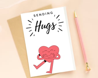 May include: A white card with the text "Sending Hugs" in black lettering. A red heart with arms and legs is hugging itself. The card is on a brown envelope.