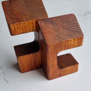 May include: A wooden sculpture made of two interlocking pieces, each with a unique shape and a smooth, brown finish.