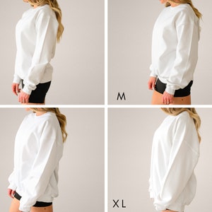 May include: Four images show a white sweatshirt in different sizes: S, M, L, and XL. The sweatshirts are plain, with a crew neck and long sleeves. The models are wearing black shorts.