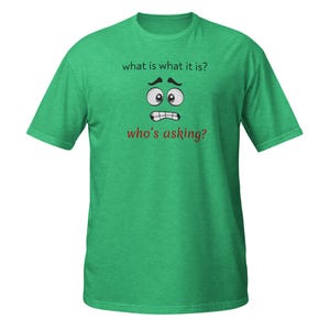 Puede incluir: Camiseta verde con el texto "what is what it is?" encima de una cara de dibujos animados con una expresión preocupada. Debajo de la cara está el texto "who's asking?"