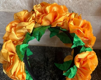 May include: A yellow flower headband with green leaves. The headband is made of satin and is perfect for a party or special occasion.