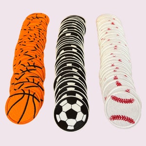 May include: A collection of sports-themed patches. The patches feature designs of a basketball in orange and black, a soccer ball in black and white, and a baseball in white and red. The patches are round and made of fabric.