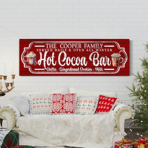 May include: A red sign with white text that reads "The Cooper Family - Served Daily & Open All Winter - Hot Cocoa Bar - Coffee, Gingerbread Cookies, Milk". The sign has a vintage look and features a drawing of a cup of hot cocoa.