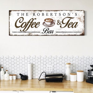 May include: A rectangular wooden sign with the text "THE ROBERTSON'S Coffee & Tea Bar" in brown lettering. The sign features a coffee cup illustration and has a distressed, vintage appearance, suitable for kitchen decor.