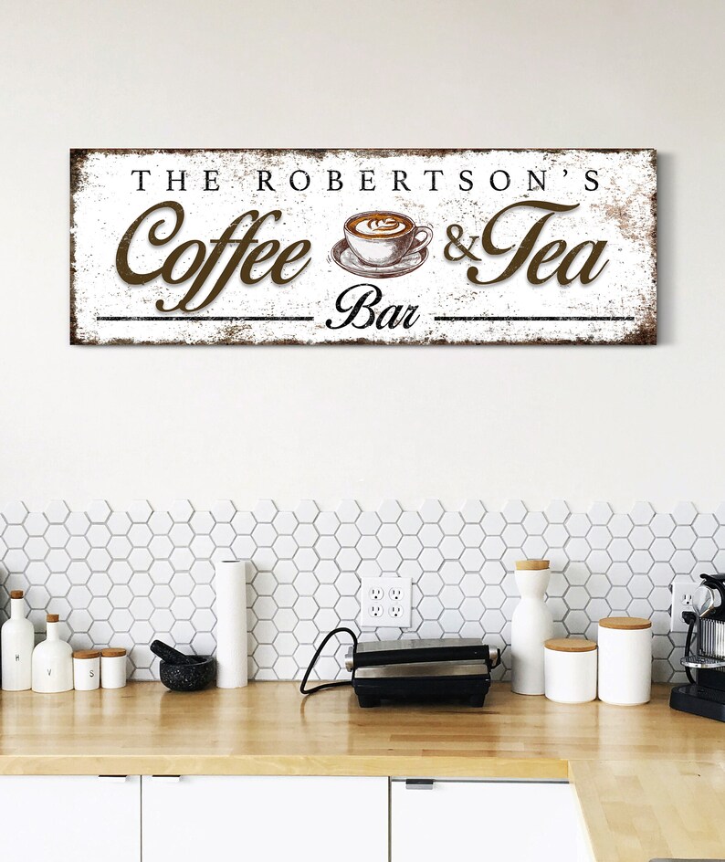 May include: A rectangular wooden sign with the text "THE ROBERTSON'S Coffee & Tea Bar" in brown lettering. The sign features a coffee cup illustration and has a distressed, vintage appearance, suitable for kitchen decor.