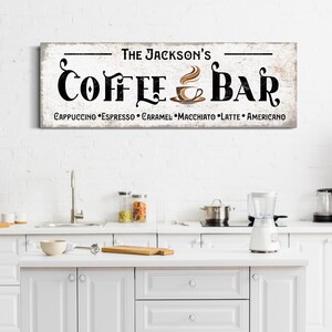 May include: A white wooden sign with black text that reads "The Jackson's Coffee & Bar" with a brown coffee cup icon and the text "Cappuccino, Espresso, Caramel, Macchiato, Latte, Americano" underneath.