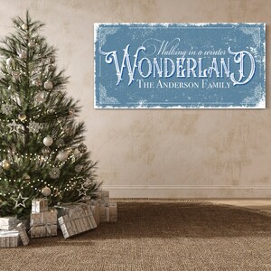 May include: A blue and white sign with the text "Walking in a winter WONDERLAND THE ANDERSON FAMILY" in a vintage style font. The sign is hanging on a beige wall with a Christmas tree in the foreground.
