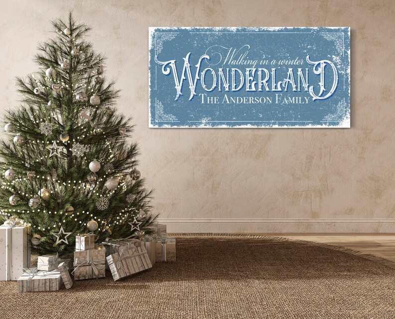 May include: A blue and white sign with the text "Walking in a winter WONDERLAND THE ANDERSON FAMILY" in a vintage style font. The sign is hanging on a beige wall with a Christmas tree in the foreground.
