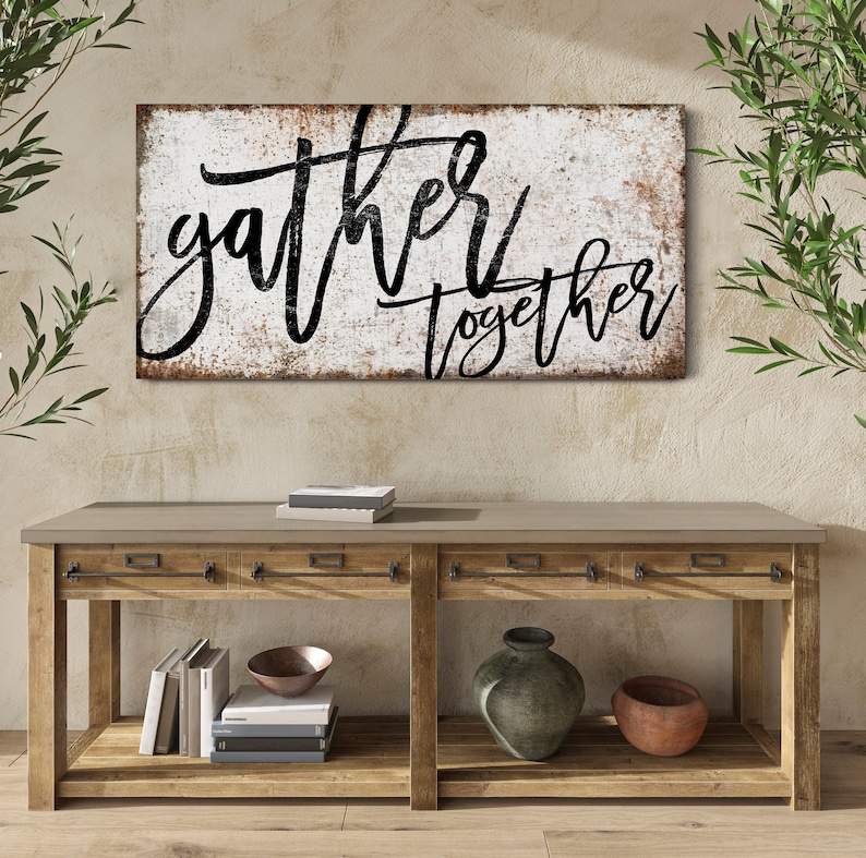 May include: A rustic wooden console table with two drawers and a lower shelf. The table has a distressed white sign above it that reads "gather together" in black script.