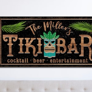 May include: A black and brown wooden sign with the text "The Miller's Tiki Bar" in white lettering. The sign also features a green and blue tiki mask and the text "cocktail, beer, entertainment".