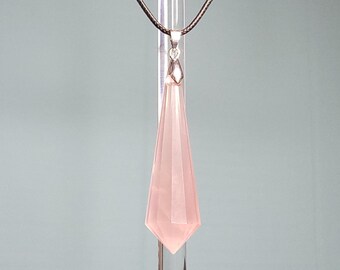 May include: A pink crystal pendant in the shape of a teardrop, hanging from a black cord necklace.