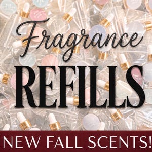 May include: A collection of small clear glass vials with gold-toned dropper caps, each featuring a round pastel-colored label. The text Fragrance REFILLS is overlaid in black, and the text NEW FALL SCENTS! appears in white on a dark red banner.