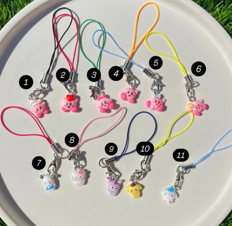 May include: Eleven colourful phone charms with pink, yellow, and white characters attached. The charms are numbered 1 through 11.