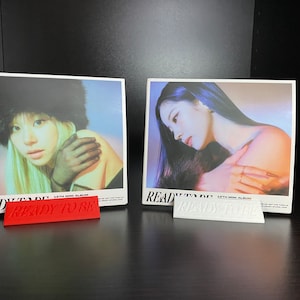 Könnte beinhalten: Zwei Albumcover mit dem Titel "READY TO BE" auf der Vorderseite. Die Albumcover zeigen eine Frau mit langen dunklen Haaren. Das erste Cover zeigt die Frau mit einem schwarzen Pelz Hut und einem schwarzen Handschuh. Das zweite Cover zeigt die Frau mit einem Pelzmantel. Beide Cover haben einen lila und blauen Hintergrund.