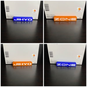 Op de afbeelding: Twee sets decoratieve blokken, een blauwe en een oranje, met de woorden "JIHYO" en "ZONE" in wit gedrukt.