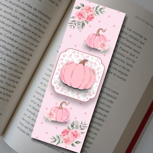 Könnte beinhalten: Ein rechteckiges Lesezeichen mit hellrosa Hintergrund und weißen Punkten, verziert mit Illustrationen von rosa Kürbissen und rosa Rosensträußen. Ein zentrales quadratisches Etikett mit gewelltem Rand zeigt eine größere rosa Kürbisgrafik.
