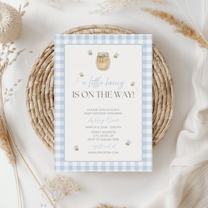 Könnte beinhalten: Babyparty-Einladung mit blauem Vichy-Karo-Rand. Die Einladung enthält den Text "a little honey IS ON THE WAY!" mit Illustrationen von Bienen und einem Honigtopf. Die Einladung enthält Details für eine Babyparty zu Ehren von Ashley Clark.