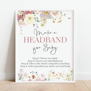 May include: A framed sign with the text "Make a HEADBAND for Baby" in pink and black script. The sign includes instructions for making a headband, with floral accents in the corners. The background is white.