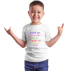 Può includere: Una maglietta bianca con un messaggio colorato che recita "Non sono te e tu non sei me Sono chi sono supposto essere".