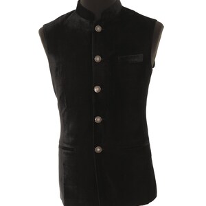 May include: A black velvet waistcoat with a mandarin collar and silver buttons. The waistcoat has two pockets and is sleeveless.