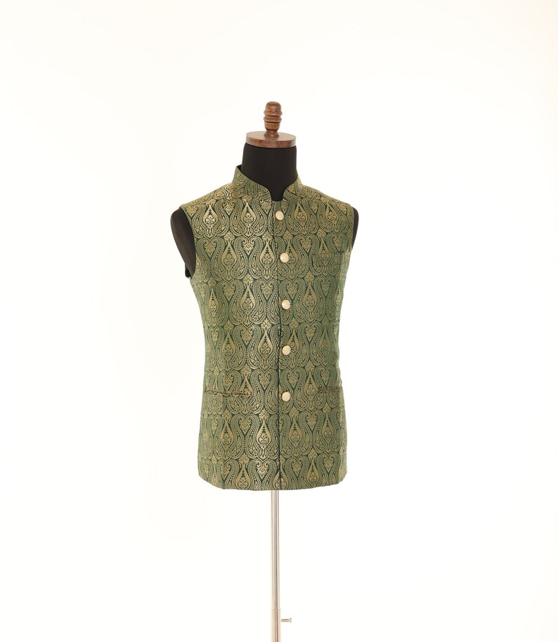K&ouml;nnte beinhalten: Eine gr&uuml;ne, &auml;rmellose Weste mit goldfarbenem Paisley-Muster und goldenen Kn&ouml;pfen.