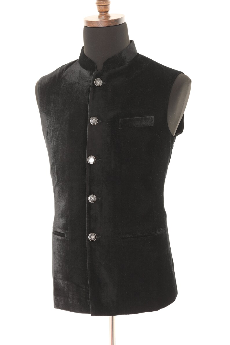 May include: A black velvet waistcoat with a mandarin collar and five silver buttons. The waistcoat has two pockets.