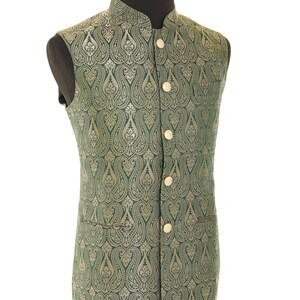 K&ouml;nnte beinhalten: Eine gr&uuml;ne Weste mit goldfarbenem Paisley-Muster und goldenen Kn&ouml;pfen. Die Weste ist &auml;rmellos und hat einen Stehkragen.