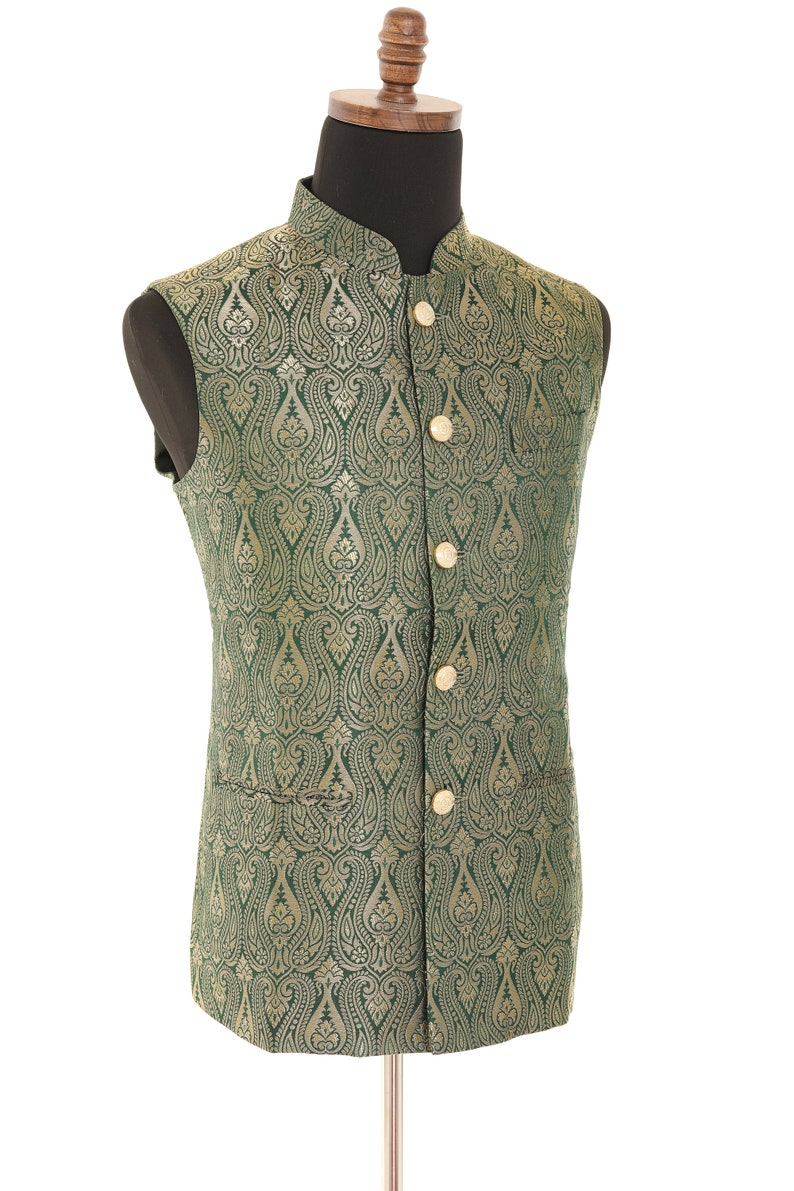 K&ouml;nnte beinhalten: Eine gr&uuml;ne Weste mit goldfarbenem Paisley-Muster und goldenen Kn&ouml;pfen. Die Weste ist &auml;rmellos und hat einen Stehkragen.