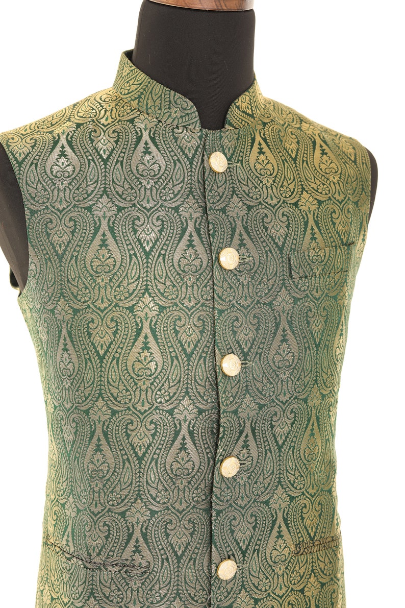 K&ouml;nnte beinhalten: Eine gr&uuml;ne Weste mit einem goldenen Paisley-Muster und goldenen Kn&ouml;pfen. Die Weste ist aus Brokatstoff.