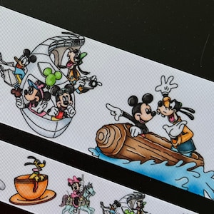 May include: White ribbon featuring cartoon characters in various scenes. Pluto is in a teacup, Minnie Mouse rides a carousel horse, and Mickey and Goofy are on a log flume. Other characters are in a boat and teacups.