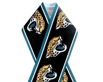 May include: A black ribbon-shaped accessory featuring a repeating pattern of a jaguar's head in gold, black, and teal. The edges are trimmed with teal and white stripes. The ribbon is likely for a sports fan.