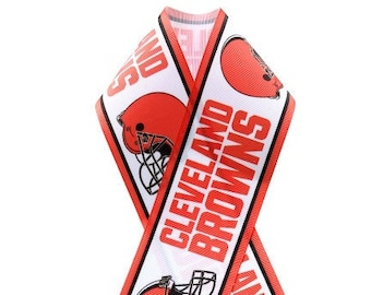 May include: White ribbon with the words "CLEVELAND BROWNS" in orange block letters and orange football helmet graphics. The ribbon has a red border and is folded into a decorative shape.