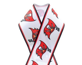 May include: White ribbon featuring a repeating pattern of a red flag with a skull and crossbones design. The ribbon has black and red trim, and is arranged in a cross shape.