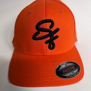 May include: Orange baseball cap with a black embroidered "SF" logo. The cap has a Flexfit label on the back with the text "The Original Flexfit L/XL It Fits Your Life."