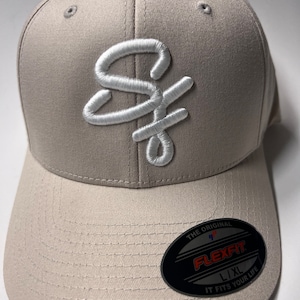 May include: A gray baseball cap with a white embroidered "SF" logo. The cap has a Flexfit label on the back with the text "The Original Flexfit L/XL It Fits Your Life."