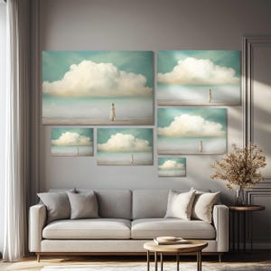 May include: A collection of five framed prints featuring a woman standing on a beach with a large cloud in the sky. The prints are arranged in a grid pattern on a wall above a gray sofa.