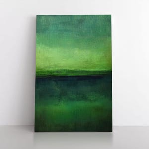 May include: Abstract landscape painting with a gradient of green hues. The artwork features a dark green base, transitioning to lighter shades of green and a horizontal dark blue line. The canvas is rectangular and leans against a white wall.