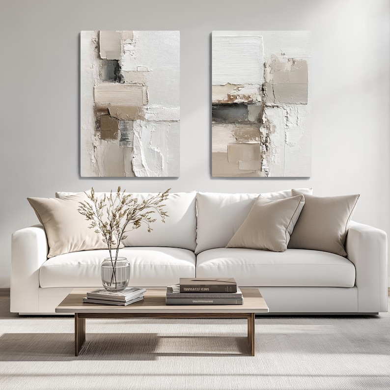 May include: Two rectangular wall art canvases featuring abstract, thick-textured paint strokes in shades of white, cream, beige, and dark gray. The compositions display layered, blocky patterns with visible impasto techniques and neutral tones.