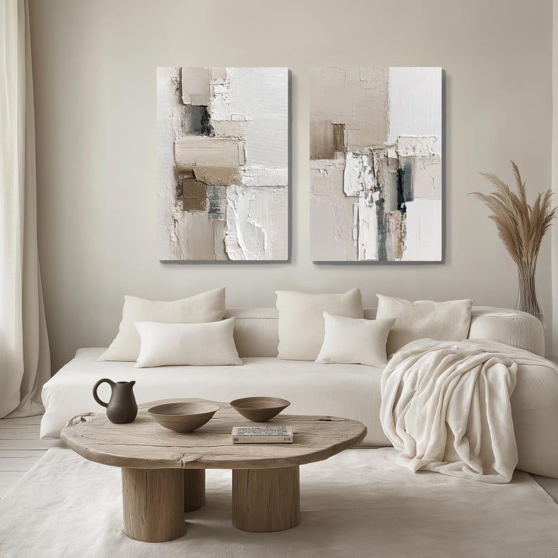 Beige and ivory abstract canvas bundle with wood coffee table, in a modern Scandinavian inspired minimalist living room, inspiring calm and serenity.