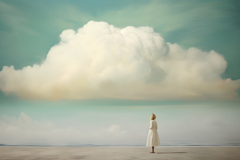 May include: A woman in a white dress stands on a sandy beach, looking out at a large, fluffy white cloud in a blue sky.