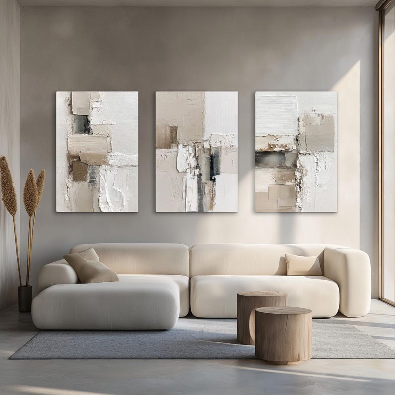 May include: A set of three vertical rectangular wall art canvases featuring abstract compositions in shades of white, cream, beige, and charcoal gray. The artwork displays thick, layered paint textures with geometric blocks and linear elements.