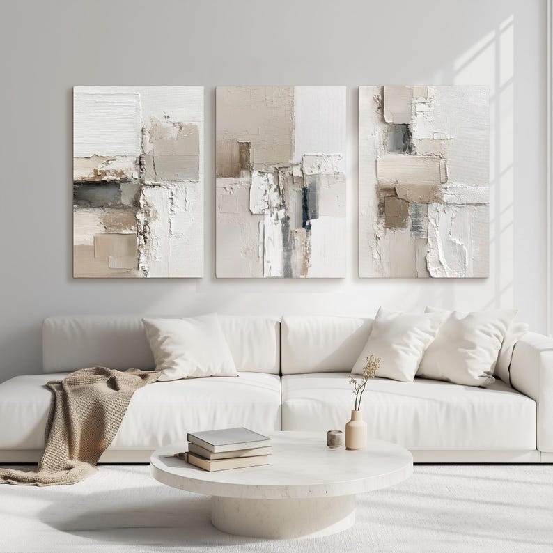 Neutral beige abstract wall art set of three above white sofa in a modern, brightly lit contemporary living room inspiring calmness
