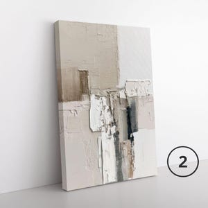 May include: A rectangular canvas wall art piece featuring an abstract composition with thick, textured paint application. The color palette consists of neutral shades including beige, cream, white, and dark gray, arranged in layered, blocky shapes.