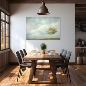 Pode incluir: Uma mesa de jantar de madeira r&uacute;stica com seis cadeiras pretas, posta com talheres e um centro de mesa de plantas verdes. Uma grande impress&atilde;o em tela de uma &uacute;nica &aacute;rvore em um campo nebuloso pendura na parede atr&aacute;s da mesa.