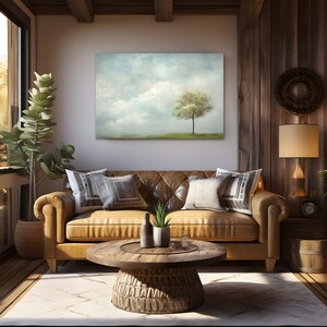 Pode incluir: Um sof&aacute; de couro marrom com almofadas fica em uma sala de estar com uma mesa de centro de madeira e uma pintura de uma &aacute;rvore em um campo com um c&eacute;u nublado acima.