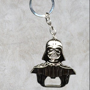 Può includere: Un apribottiglie in metallo argentato a forma di testa di Darth Vader. L'apribottiglie ha un anello per attaccarlo a un portachiavi.