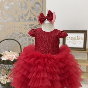Valeria Dress red. Red tiered puffy knee length baby girl dress. Red birthday and christmas dress with big bow in shiny lace fabric. Toddler
