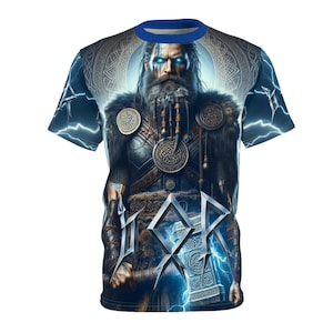 May include: A short-sleeved t-shirt featuring a detailed illustration of a Norse god with blue eyes and a long beard. The design includes lightning bolts and a hammer, with a blue collar.
